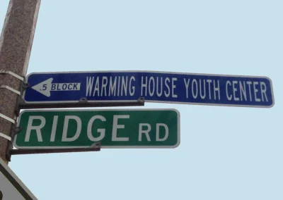 Photo of a street sign that reads warming house youth center.